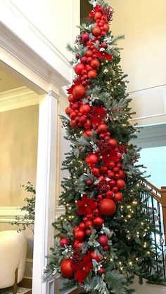 a christmas tree decorated with red ornaments and greenery in the corner of a room