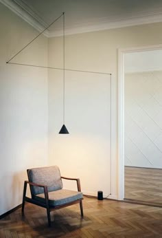 a chair sitting on top of a hard wood floor next to a wall mounted light