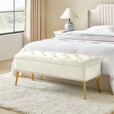 a white bed with a tufted headboard and foot stool in front of it