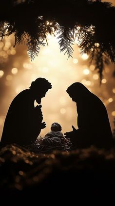 the silhouettes of two people and a baby in a manger with lights behind them