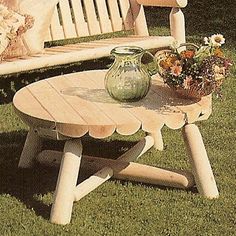 two wooden benches sitting on top of a grass covered field next to a vase with flowers