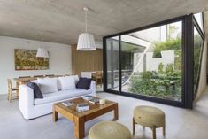 a living room with white couches and wooden tables in front of glass doors that lead to an outdoor deck