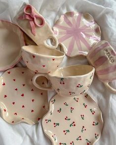 a pile of ceramic dishes with bows and hearts painted on them sitting on a white sheet