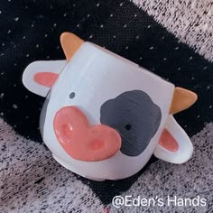 a cow shaped mug sitting on top of a black and white carpeted floor next to a rug