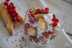 a dessert dish with fruit and whipped cream in a glass bowl on a wooden board