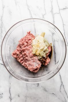 a bowl filled with meat and cheese on top of a marble counter