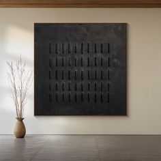 a vase sitting in front of a black wall mounted on a wall next to a plant