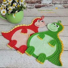 two crocheted rugs sitting next to each other on a wooden floor with flowers in the background