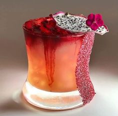 a red drink with a slice of fruit on the rim and sprinkles