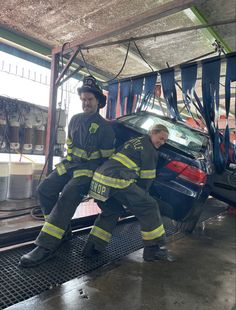 two fire fighters sitting on the back of a car