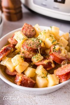 a white bowl filled with potatoes and meat next to an instant pot pressure cooker