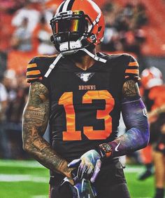 a football player with tattoos on his arm and hand is holding a glove in front of him