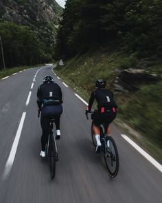 two bicyclists are riding down the road together