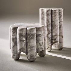 two marble stools sitting next to each other on top of a white flooring