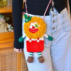 a woman wearing a crocheted bag with a clown face on it's back