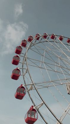 a ferris wheel with red seats on it's side and blue sky in the background