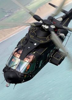 a black helicopter flying over the ocean