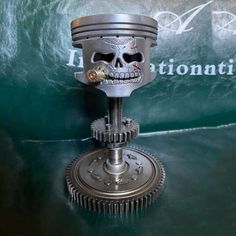 a metal clock with a skull face on it's side and gears in the middle