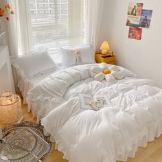 a bed with white comforters and pillows on it in a bedroom next to a window