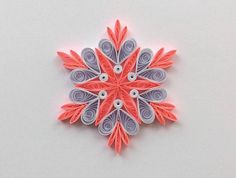 an origami snowflake made out of red, grey and white paper