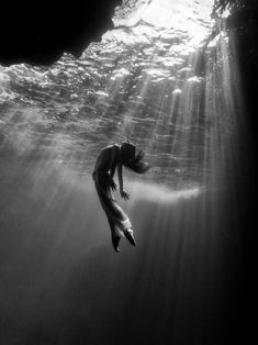 a woman is swimming under the water in black and white