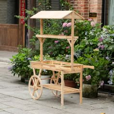 a wooden cart sitting on the side of a road next to flowers and potted plants