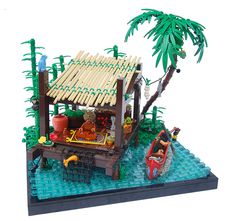 a lego model of a hut with people on the deck and in a boat near a palm tree