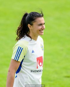 a female soccer player smiles as she walks on the field with her hair in a ponytail