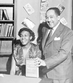 a man and woman standing next to each other in front of a bookshelf