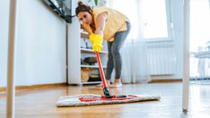 a woman cleaning the floor with a mop in her hand and wearing yellow gloves