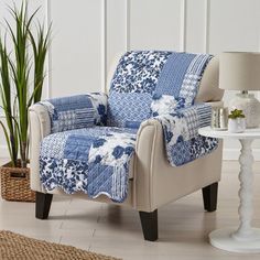 a blue and white patchwork recliner chair next to a table with a potted plant