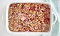 a white casserole dish filled with beans and meat