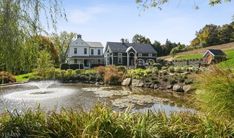 a large house sitting on top of a lush green hillside next to a lake and forest