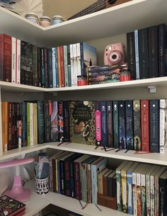 a book shelf filled with lots of books on top of white shelving unit shelves