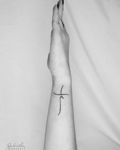 a person's foot with a small cross tattoo on the left side of their arm