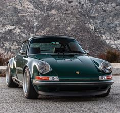 a green sports car parked in front of a mountain