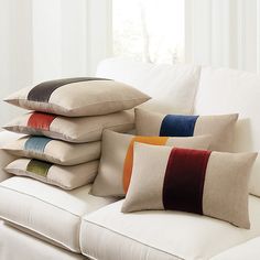 pillows stacked on top of each other on a white couch in front of a window