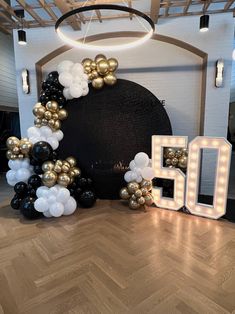 the balloon arch is decorated with black, white and gold balloons that spell out 50