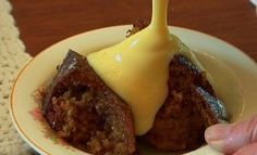 a white plate topped with cake covered in yellow sauce on top of a wooden table