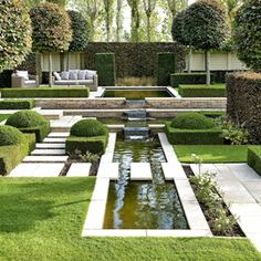 a formal garden with water feature in the center and seating area on either side, surrounded by green grass