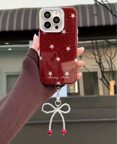 a person holding up a red phone case with white stars and a bow on it