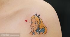 a woman's shoulder with a tattoo of a cartoon character and a heart on it