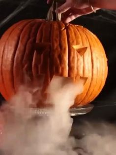 a carved pumpkin sitting on top of a metal pan with steam coming out of it