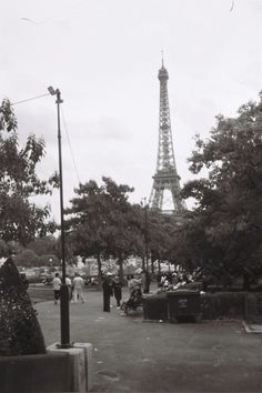 the eiffel tower is in the distance with people walking around it and cars parked on the street