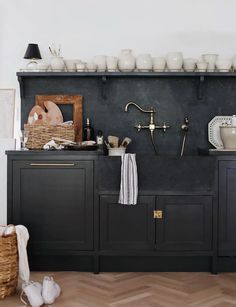 a kitchen with black cabinets and white dishes on the top shelf in front of it