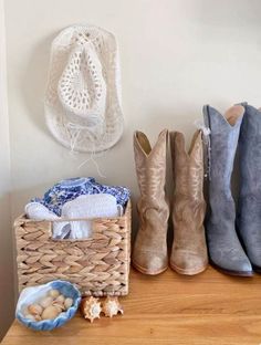 four pairs of cowboy boots sitting on top of a wooden table next to a basket