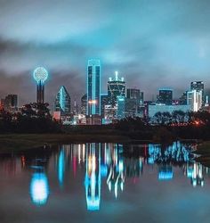 the city skyline is lit up at night, with bright lights reflecting in the water