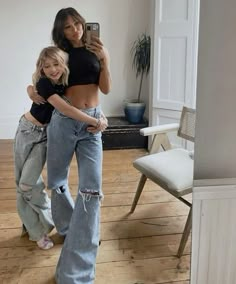 two women standing in a room with one taking a selfie