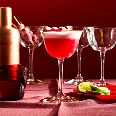 three glasses filled with different types of drinks on top of a pink table cloth covered table