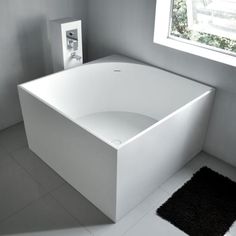 a white bath tub sitting in a bathroom next to a black and white rug on the floor